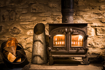 Wood burner, wood burning stove in old stone fireplace, UK