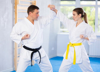 Obraz premium Sparring woman and man in white kimono during karate training in the gym