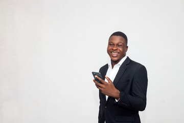 Happy handsome amazed african businessman on black suit using smartphone, chatting online, texting message, browsing internet, social media, looks at camera, excited stand over a white background