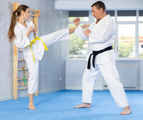 Obraz premium Young woman and man training block and kicks in gym