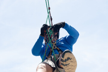 Rappeller hanging from rope checking safety equipment. Healthy and dangerous sport.