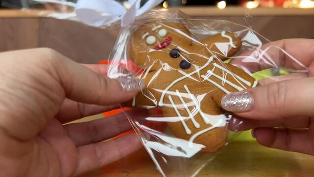 gingerbread man Gift for Christmas delicious cookies take out from packaging dance beautiful toy delicacy female hands with shiny Christmas manicure Present yami. symbol of winter New Year