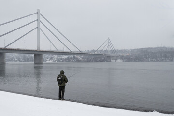 fisherman on winter Danube river in front of cable-bridge, Novi Sad