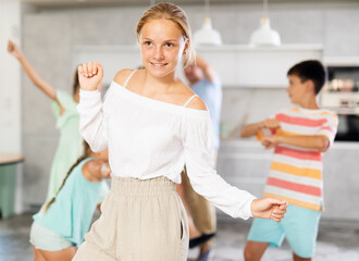Fototapeta premium Behind cheerful positive girl, big family of parents, sisters, brother is rejoicing, dancing, having fun. Family with school-age children celebrates important event date