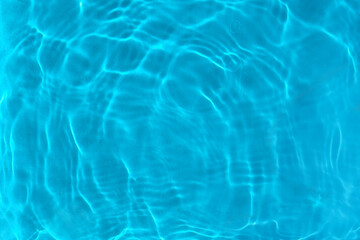 Transparent blue clear water surface texture with ripples, waves and rings in sunlight. Abstract nature aqua background, sunny reflections