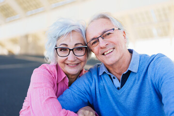 Senior couple taking a selfie while smiling sitting together in the city