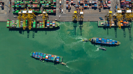 Fototapeta na wymiar commercial port loading and unloading cargo from container ship import and export by crane for distributing goods by trailers transported to customers and dealers, aerial top view