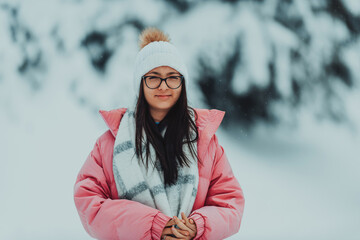 Fototapeta na wymiar In a picturesque snowy landscape, a charming woman in a pink jacket and white hat exudes joy and style on a beautiful winter day