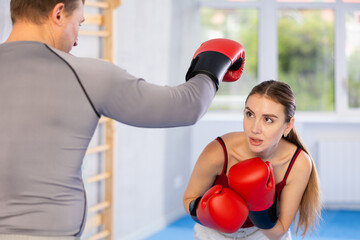 Athletic woman learns to box in ring with a male trainer