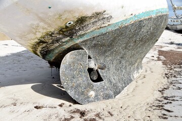 boat washed ashore on beach with propeller