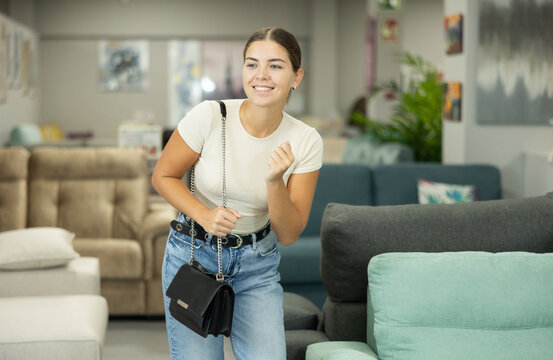 Female shopper browses trendy furniture store in search of perfect goods. She carefully examines assortment on display, determined to find ideal piece to elevate aesthetic of her living area.