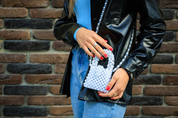 A stylish handbag in the hands of a young woman. Background with selective focus and copy space