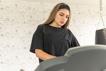 young woman setting up her workout on a treadmill