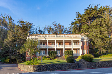 scenic historic houses in battery park near golden gate bridge in green landscape in San Francisco,
