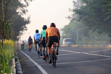 rear view of a group of people cycling in the morning with morning sunlight.  cycling to maintain fitness and a healthy lifestyle.