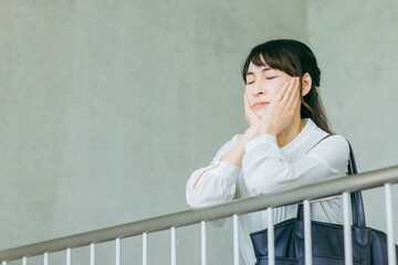 階段の踊り場で手すりに頬杖をつくビジネスウーマン
