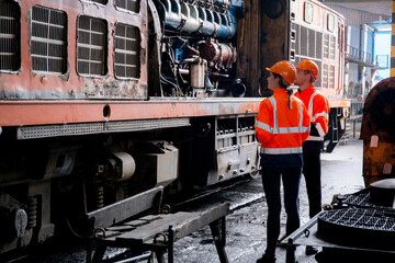 Young caucasian engineer man and woman check and maintenance engine of train in station, team engineer inspect system transport, technician checking infrastructure, transportation and industry.