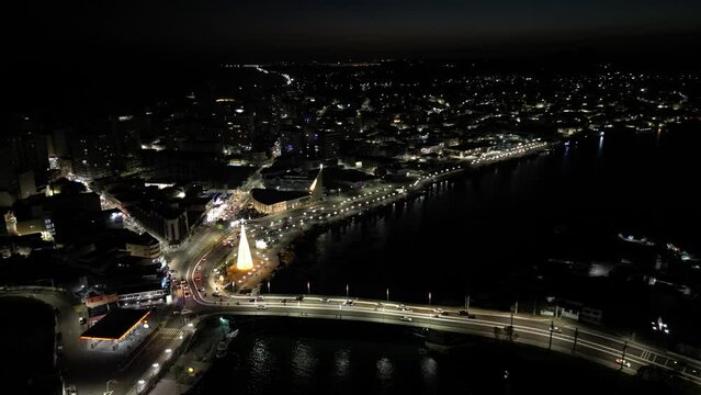 Imagem a&eacute;rea de drone da cidade de Guarapari a noite, praia do morro e prainha de muqui&ccedil;aba iluminadas. Decora&ccedil;&atilde;o de natal e festas de final de ano.
