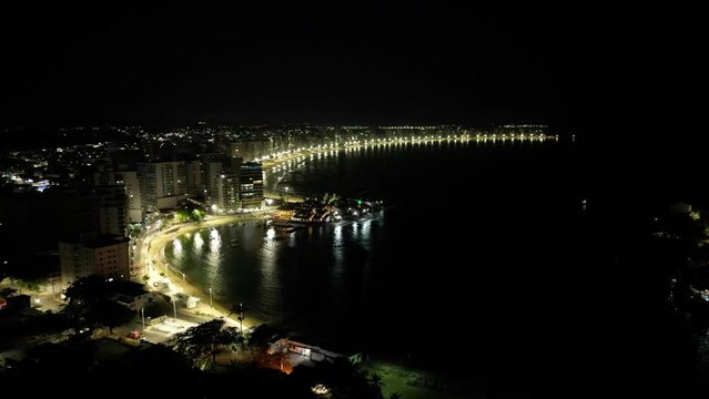 Imagem a&eacute;rea de drone da cidade de Guarapari a noite, praia do morro e prainha de muqui&ccedil;aba iluminadas. Decora&ccedil;&atilde;o de natal e festas de final de ano.