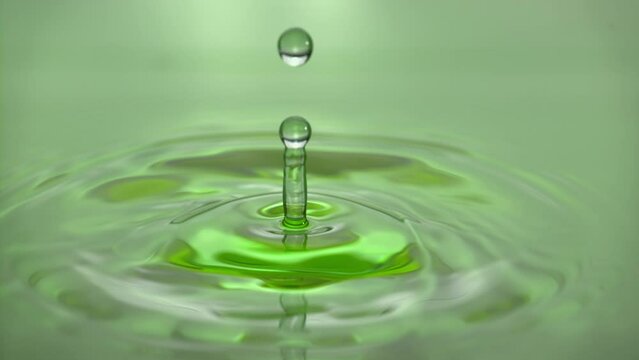 Beautiful closeup splash of green serum drop in slow motion. Cosmetic essence serum falling in slow motion. Body moisturizing cosmetics formulating commercial product. Green tea or aloe vera extract