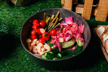 Assorted Pickled Vegetables in Rustic Bowl on Faux Grass. An appetizing assortment of pickled vegetables including sauerkraut, ramps, garlic, cherry tomatoes, and lightly pickled cucumbers.