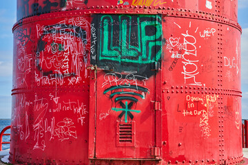 Red Lighthouse with Vibrant Graffiti Art by the Sea