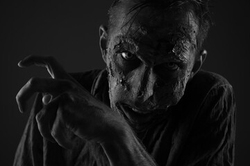 Scary zombie on dark background, black and white effect. Halloween monster