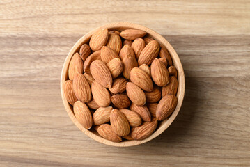 Raw almond in bowl on wooden background, Table top view