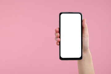 Woman holding smartphone with blank screen on pink background, closeup. Space for text