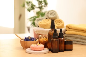 Dry flowers, soap bar, bottles of essential oils and jar with cream on wooden table indoors. Spa time