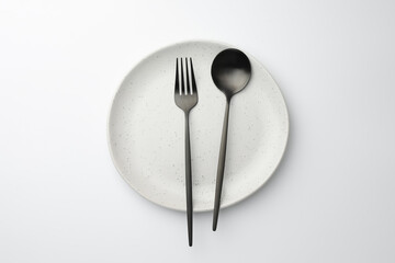 Plate, fork and spoon on white background, top view