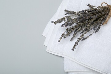 White terry towels and lavender flowers on light grey background, top view. Space for text - obrazy, fototapety, plakaty