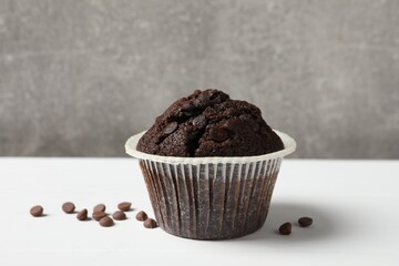 Tasty chocolate muffin on white table against grey background