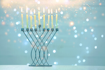 Hanukkah celebration. Menorah with burning candles on table against blurred lights, space for text