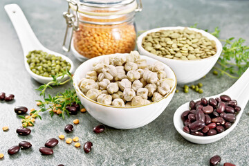 Legumes in bowls and spoons on granite table