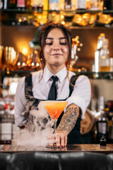 Young female bartender offering a drink