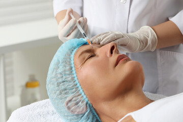 Obraz na płótnie Canvas Doctor giving facial injection to senior woman in clinic, closeup. Cosmetic surgery