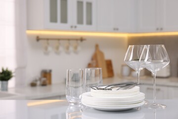 Set of clean dishware, glasses and cutlery on table in kitchen, space for text