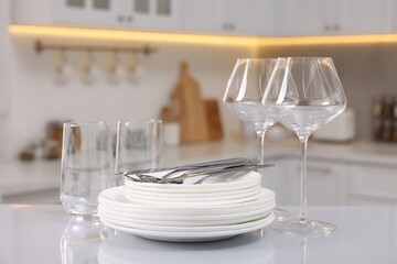 Set of clean dishware, glasses and cutlery on table in kitchen