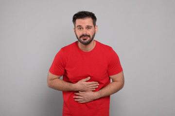 Man suffering from stomach pain on grey background