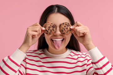 Young woman with chocolate chip cookies on pink background - Powered by Adobe