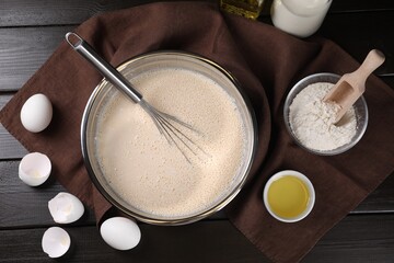 Flat lay composition with whisk and dough in bowl on wooden table