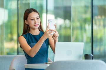 Asian business woman using smartphone with laptop