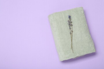 Soft towel and lavender flowers on violet background, top view. Space for text