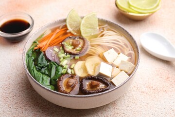 Bowl of vegetarian ramen served on color textured table, closeup