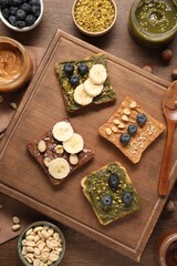 Toasts with different nut butters, blueberries, banana slices and nuts on wooden table, flat lay