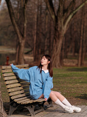 Fototapeta premium Beautiful young Chinese woman posing in sunny summer forest, wearing blue loose oversized top and miniskirt with small shoulder bag. Emotions, people, beauty, youth and lifestyle portrait.