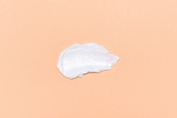 Smear of moisturizing cream against backdrop of trendy peach color.