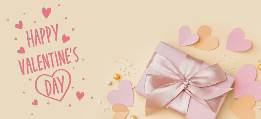 Greeting banner for Valentine's Day with beautiful paper hearts and gift on beige background
