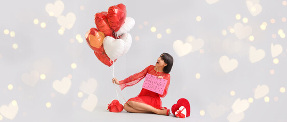 Surprised young woman with heart-shaped air balloons and gifts on grey background. Valentine's day...